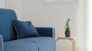A blue armchair with a cushion, a small wooden side table with a potted plant, and a mirror on the wall. - TWO ROOMS SEA VIEW APARTMENT (FORIO)