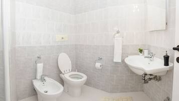 Un bagno dotato di due servizi igienici, un bidet, un lavandino e uno specchio.