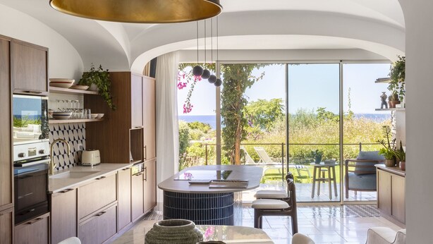Une cuisine moderne avec une grande table à manger, un luminaire suspendu et une vue sur l’extérieur.