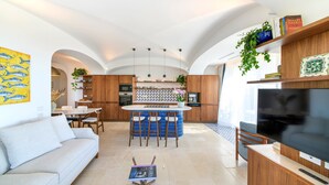 Une cuisine moderne dotée d’un îlot central, de tabourets de bar et d’un coin repas avec une table et des chaises blanches.