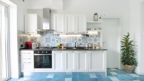 A modern kitchen with white cabinets, a blue-tiled backsplash, and a black stove. - NEW DELUXE STUDIO WITH PRIVATE GARDEN AND TERRACE (Forio)
