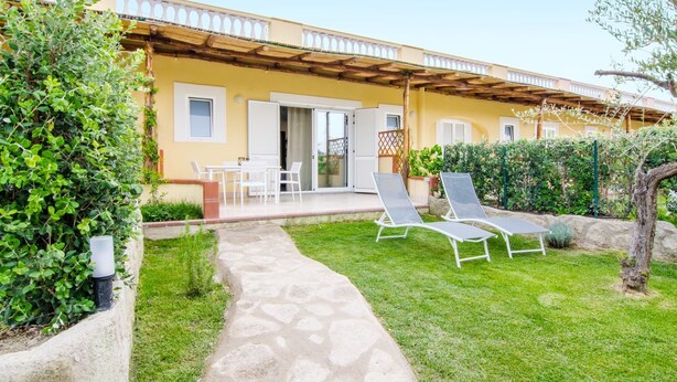 A yellow building with a covered patio, outdoor seating, and a stone pathway. - NEW DELUXE STUDIO WITH PRIVATE GARDEN AND TERRACE (Forio)