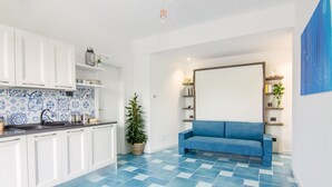 A modern kitchen with white cabinets, blue patterned backsplash, and a blue tiled floor. - NEW DELUXE STUDIO WITH PRIVATE GARDEN AND TERRACE (Forio)