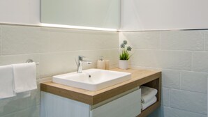 A modern bathroom with a white sink, wooden countertop, and a small potted plant. - NEW DELUXE STUDIO WITH PRIVATE GARDEN AND TERRACE (Forio)