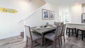 A dining area with a table set for four, chairs, and a staircase leading to another level. - Margaritaville Fun in the Sun - Townhome (Kissimmee)