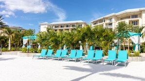 A beachfront hotel with rows of blue lounge chairs, palm trees, and a clear blue sky. - Margaritaville Fun in the Sun - Townhome (Kissimmee)