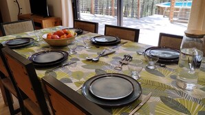 Een eettafel gedekt voor zes personen met uitzicht op een zwembad en bomen.