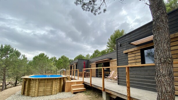 Een houten chalet met terras, hottub en uitzicht op het omliggende bos.