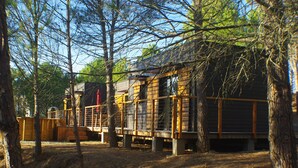 Een chalet met terras, omgeven door bomen.