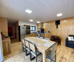 A modern kitchen with wooden cabinets, a dining table with chairs, and a blue sofa.