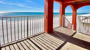 Una terraza de madera con barandilla que da a una playa.
