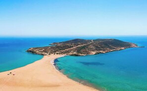Vista aérea de una playa con aguas turquesas cristalinas y una orilla arenosa.