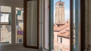 A room with a window overlooking a historic building with a bell tower. - Ca Dandolo, finely refurnished  (Venice)