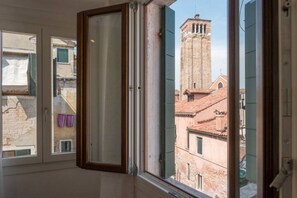 Una stanza con una finestra che si affaccia su un edificio storico con un campanile.