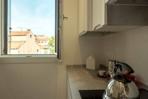 Una cocina con ventana, tetera y cafetera.