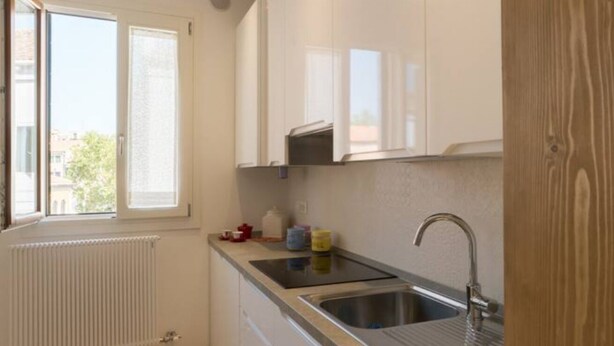 A kitchen with a window, white cabinets, a sink, and a radiator. - Ca Dandolo, finely refurnished  (Venice)
