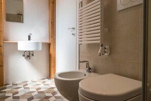 Une salle de bain équipée d’un lavabo, d’un bidet, de toilettes et d’un porte-serviettes.
