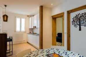 Une pièce avec une table ronde, une chaise, un luminaire suspendu, une fenêtre et une porte décorée d’un motif représentant un arbre.
