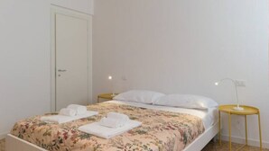 A single bed with floral bedding, a bedside table with a lamp, and a door to the left. - Ca Dandolo, finely refurnished  (Venice)