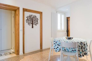 Una habitación con una mesa de comedor, sillas, un cuadro de pared con motivos de árboles y una ventana.