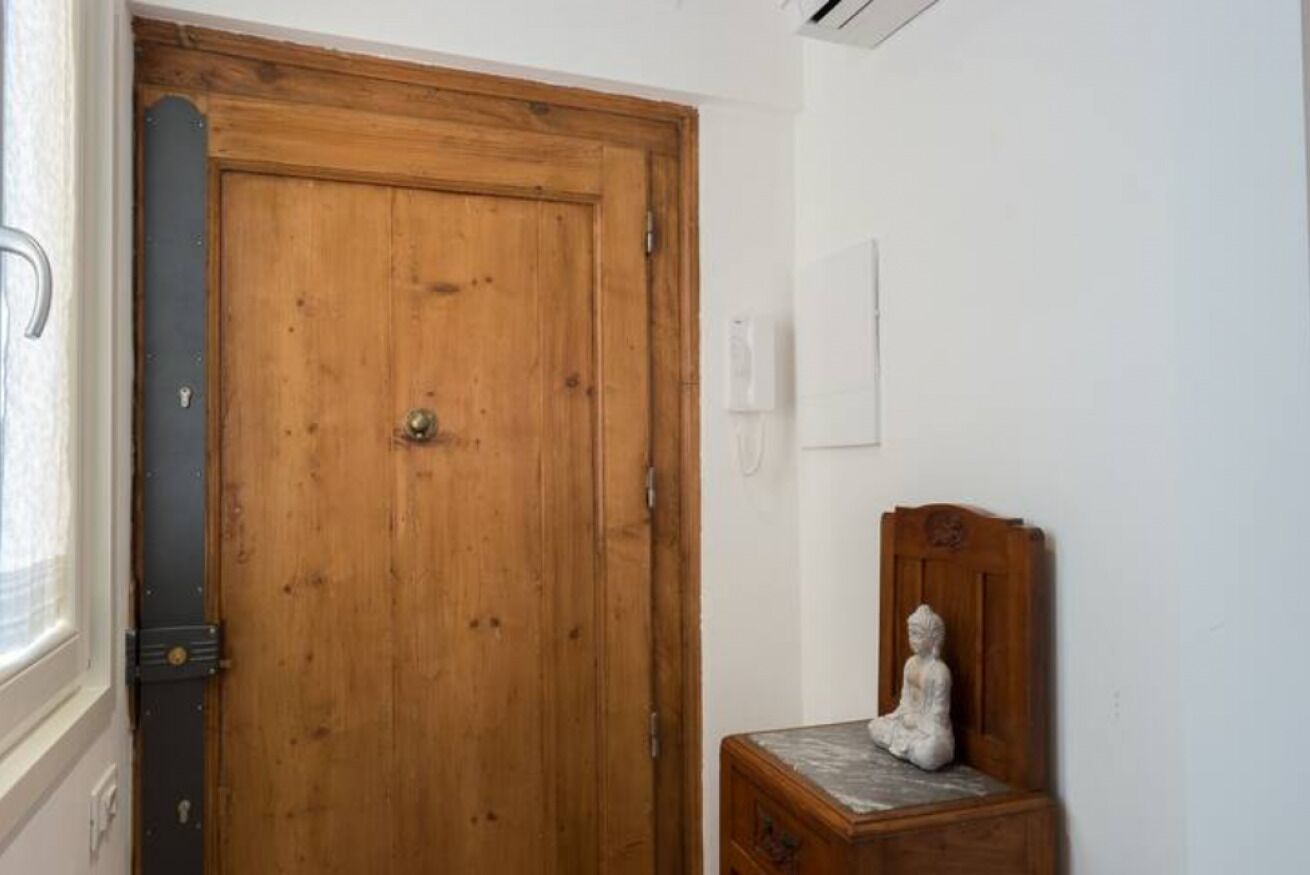 Una puerta de madera con una pequeña estatua sobre una mesa de madera a su lado.
