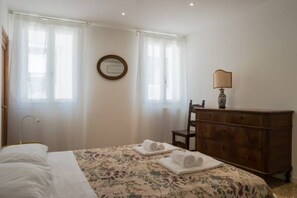 Une chambre d’hôtel avec un lit, une commode, un miroir et une lampe.