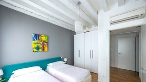 A room with two beds, a teal headboard, a white wardrobe, and a colorful abstract painting on the wall. - Rialto al Manganer, apartment near Rialto Mercato (Venezia)