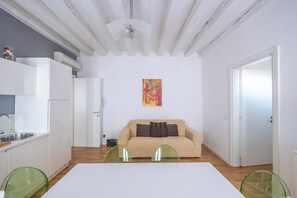 Een ruimtelijk ingedeelde leefruimte met een kitchenette, een bank en een eethoek.