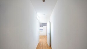 A narrow hallway with wooden flooring leading to a kitchen area.