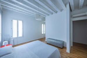 A modern bedroom with a large bed, a bench, and a wardrobe.