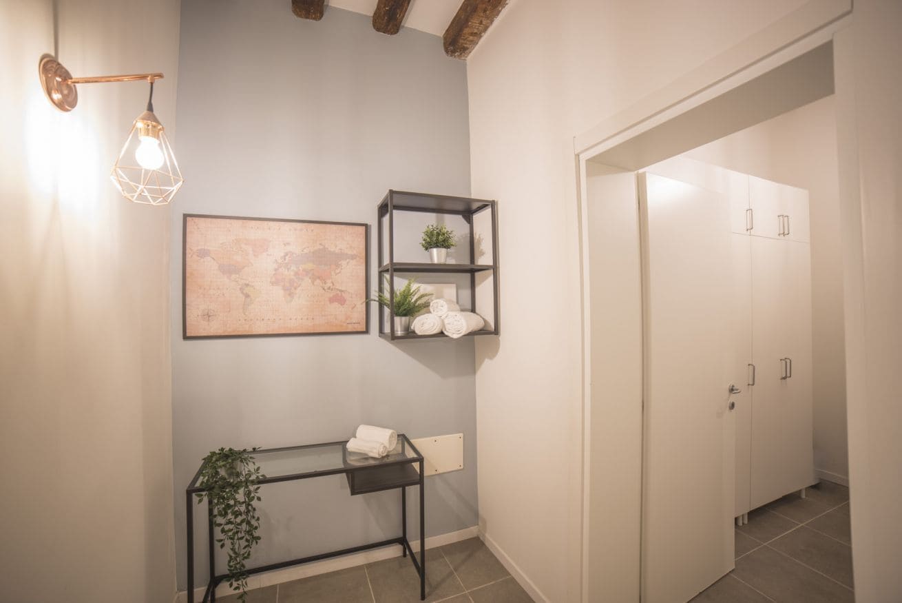 Ein Flur mit einer Karte an der Wand, einem Metall-Konsolentisch mit einer Pflanze und einem weißen Wandschrank.