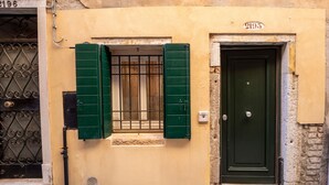 Une façade d’immeuble avec une porte verte et une fenêtre dotée de volets verts.