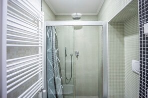 A shower area with a glass door, tiled walls, and a white ceiling.
