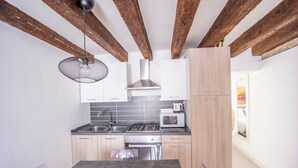 Une cuisine moderne avec des poutres apparentes, une cuisinière à gaz, un four à micro-ondes et un évier.
