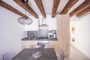 A modern kitchen with exposed wooden beams, a gas stove, a microwave, and a sink.