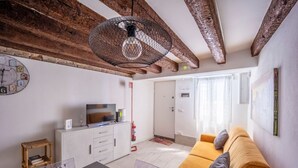 Un salon moderne avec des poutres apparentes, un canapé, un téléviseur et un coin repas.