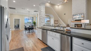 A spacious kitchen with white cabinets, a granite countertop, and a stone accent wall.