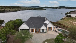 A house with a large front yard, a swimming pool, and a view of a lake.