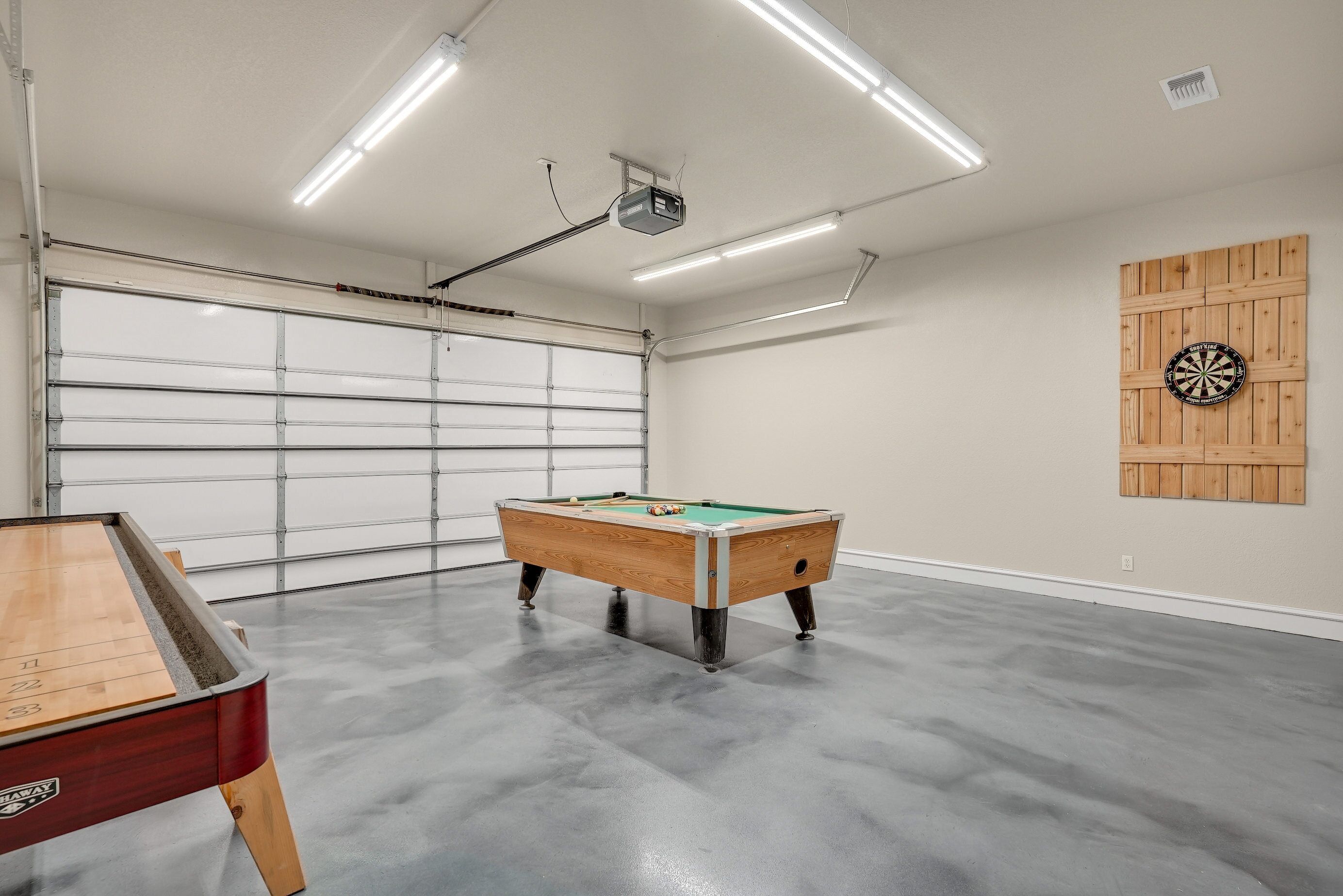 Un amplio espacio interior con mesa de billar, mesa de fútbol de mesa y dardos en la pared.