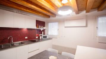 A modern kitchen with white cabinets, a red-tiled backsplash, a microwave, and a sink.