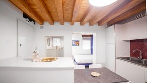 A modern kitchen with white cabinets, a marble countertop, and a wooden ceiling. - Ca' Gritti, Castello next to Arsenale (Venezia)