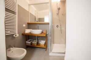 Un baño moderno con lavamanos, espejo y ducha.
