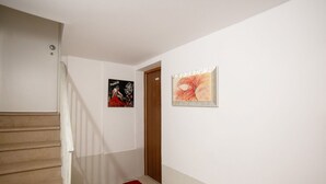 A hallway with a wooden staircase, a red rug, and two framed artworks on the walls. - Ca' Gritti, Castello next to Arsenale (Venezia)