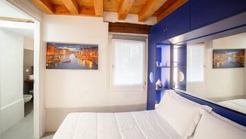 A bedroom with a large bed, a wooden ceiling, and two paintings of a cityscape.