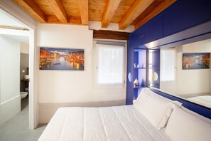 Un dormitorio con una cama grande, techo de madera y dos cuadros de un paisaje urbano.