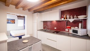 A compact kitchen with a red tiled backsplash, white cabinetry, and a microwave on the countertop. - Ca' Gritti, Castello next to Arsenale (Venezia)