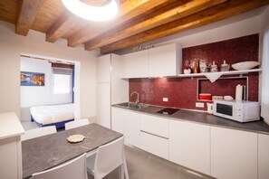 Una cocina compacta con salpicadero de baldosas rojas, armarios blancos y un microondas en la encimera.
