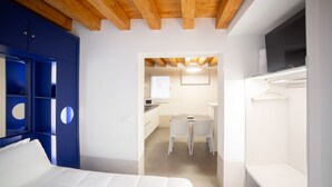 A bedroom with a bed, a wardrobe, and a TV. There is a small kitchenette with a table and chairs. - Ca' Gritti, Castello next to Arsenale (Venezia)