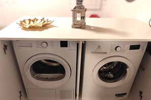 Deux machines à laver à chargement frontal, dotées de panneaux de commande, d’une coque décorative et d’une petite lanterne sur le dessus.