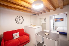 A compact living space with a red sofa, a small dining table, and a white kitchenette. - Ca' Gritti, Castello next to Arsenale (Venezia)